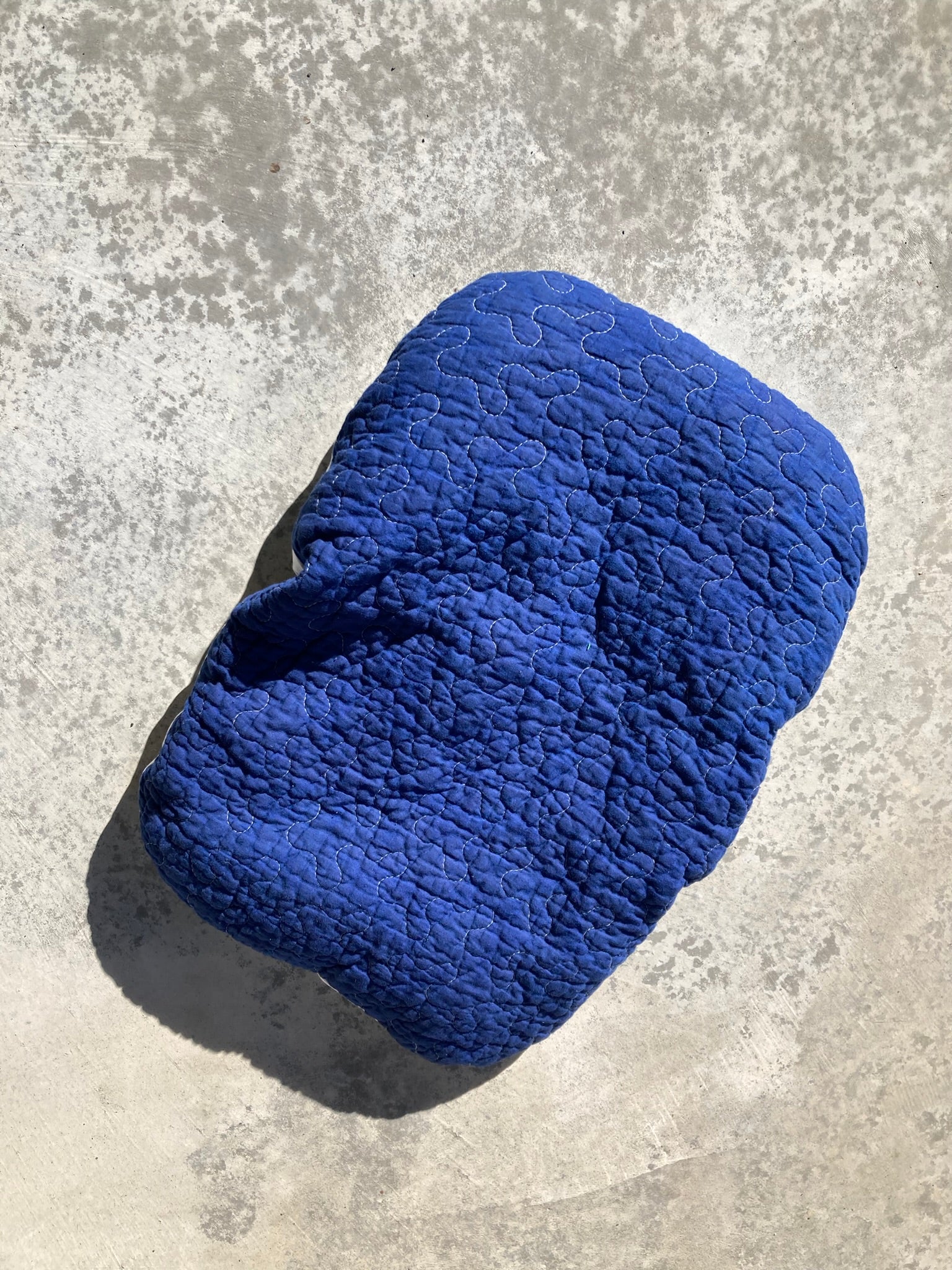 The cobalt pet pillow on a concrete background.