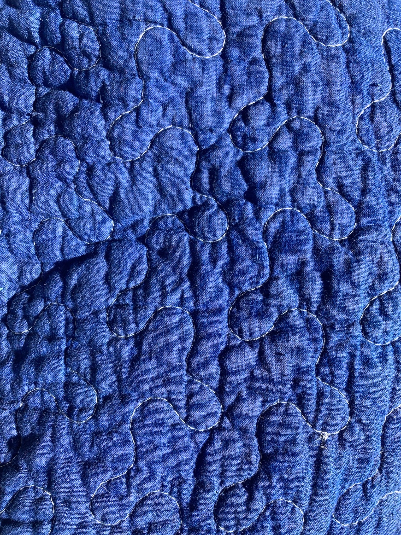 Close-up of the cobalt pet pillow, showing the random squiggle quilting pattern in white thread.