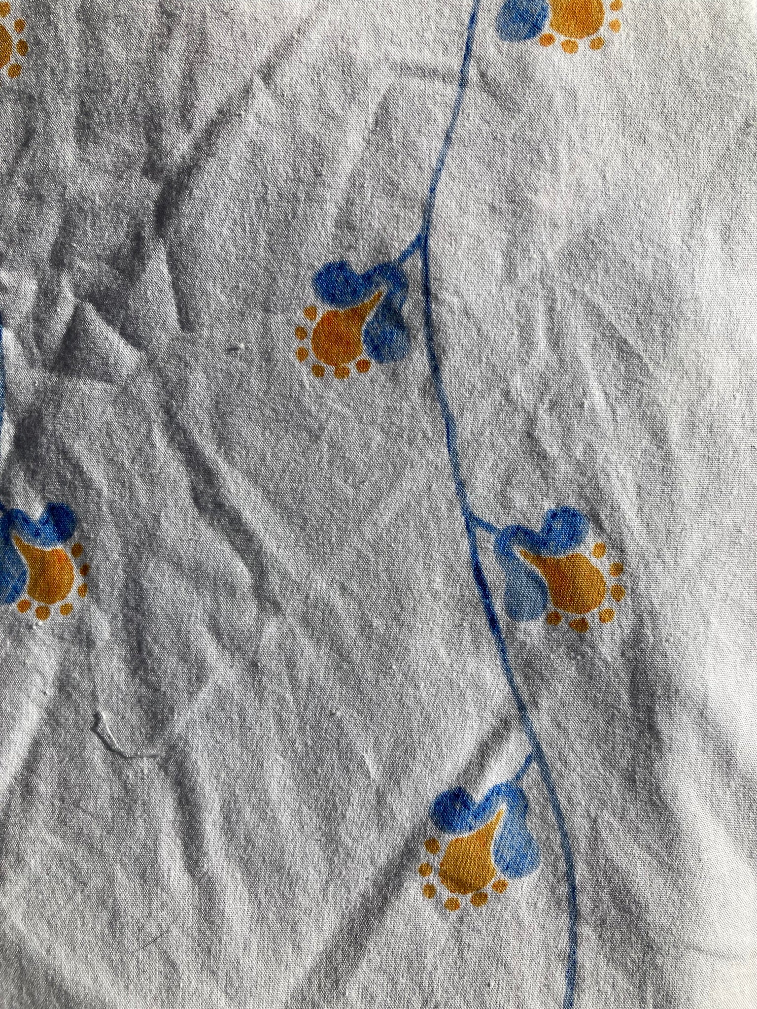 Close-up of the backing fabric for the cobalt pet pillow. This shows the pattern is blue vines with small mustard yellow flowers on a white background.