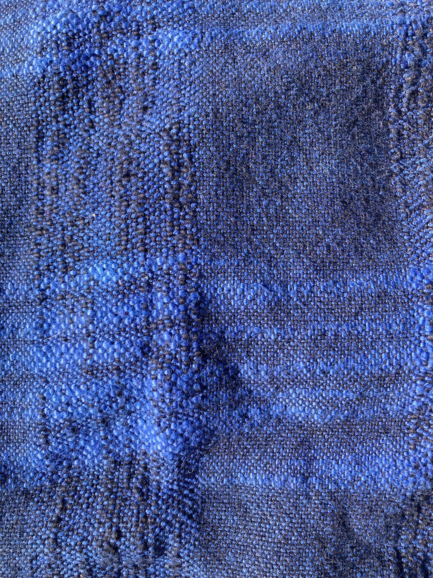 Close-up of the woven blue pet pillow top shows the texture of the weave and the pattern of bright blue and deep navy threads.