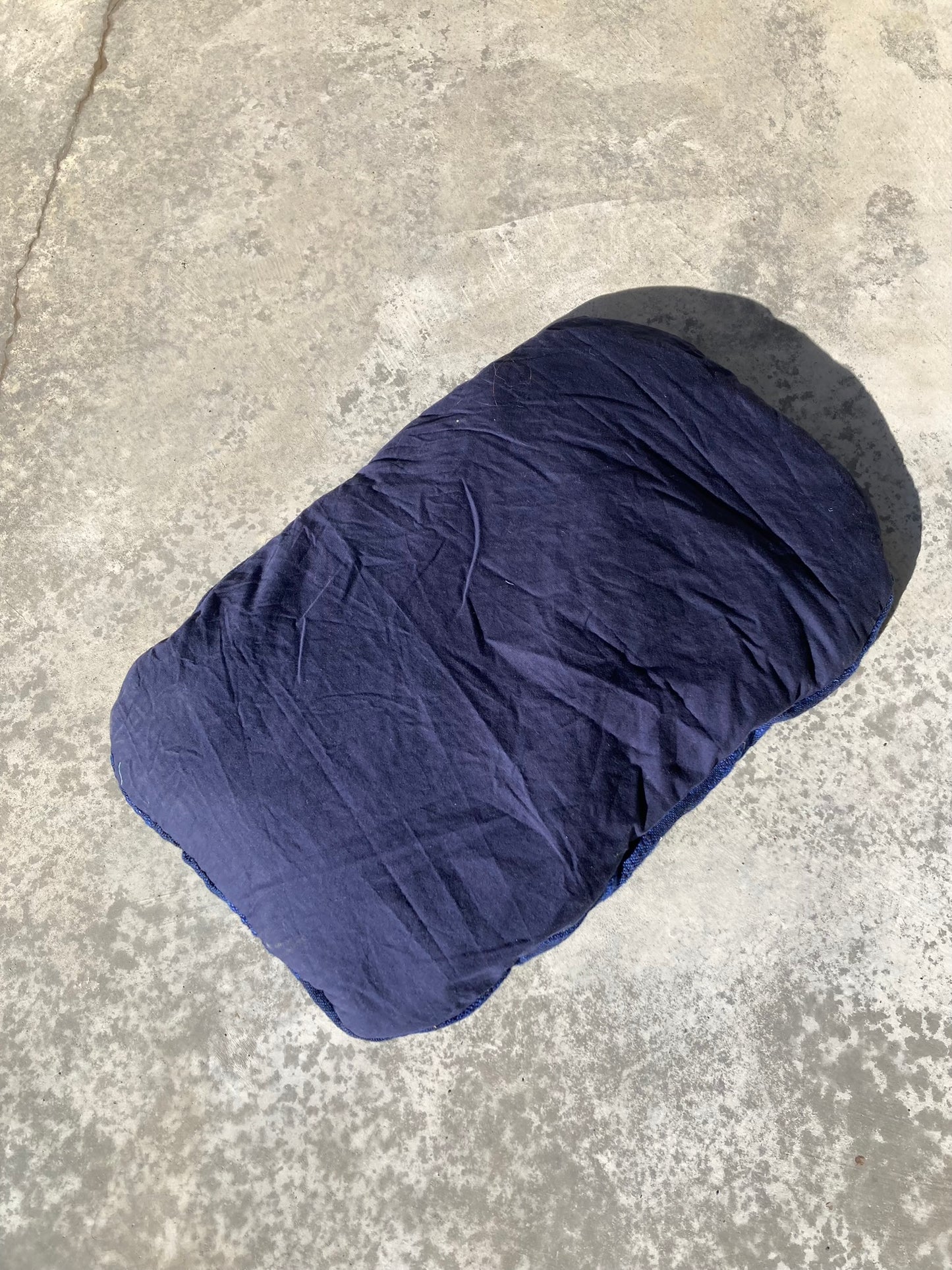 The backing fabric of the woven blue pet pillow, which is a plain navy cotton.