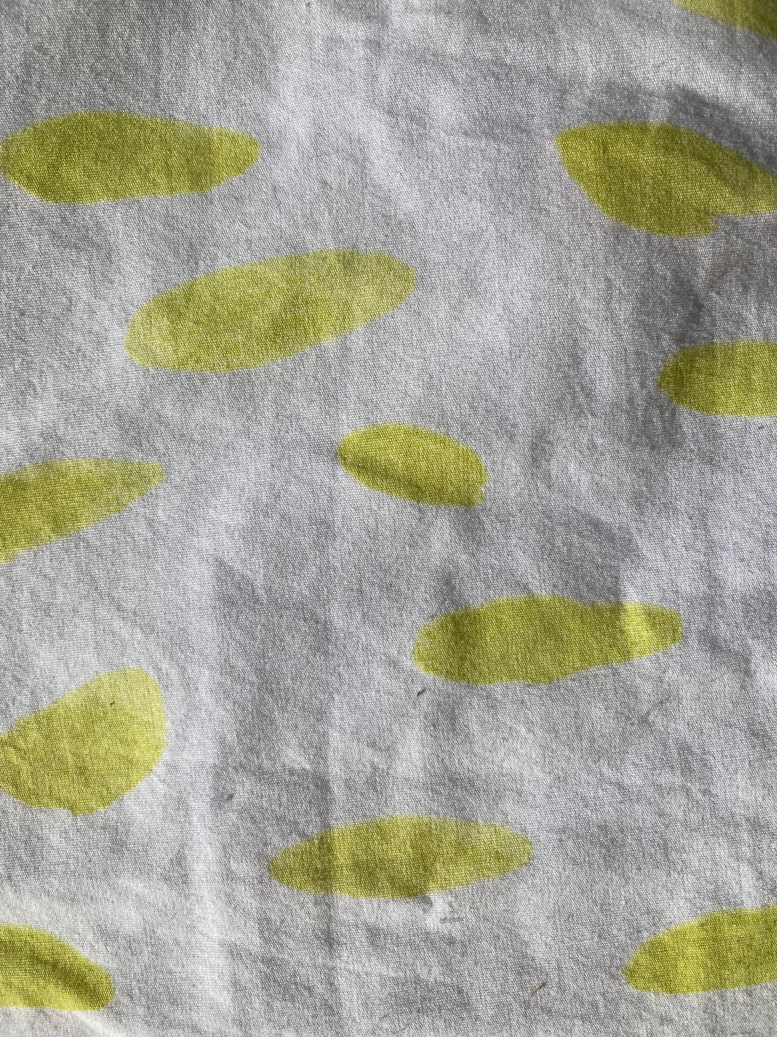 The backing fabric of the line green pet pillow, which is white with organic ovals in lime green.