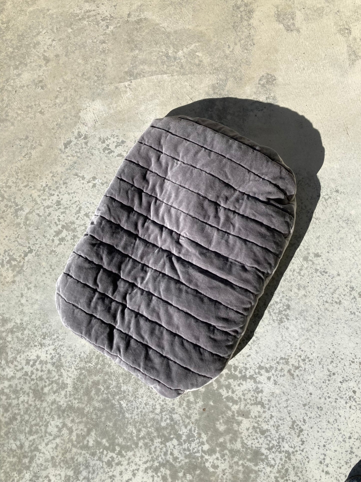 Grey velvet pet pillow on concrete background.