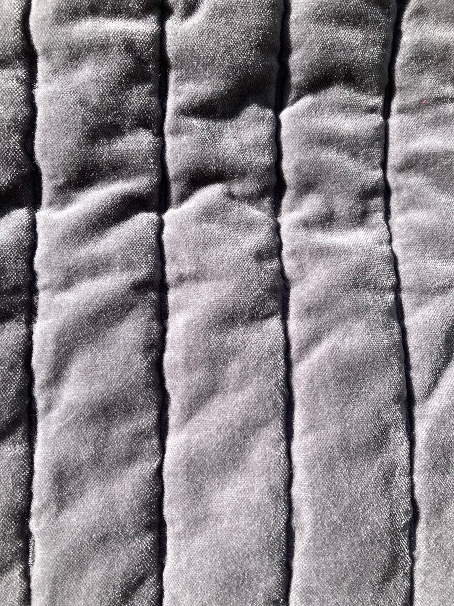 Close-up of grey velvet pet pillow top, showing the straight line quilting pattern.