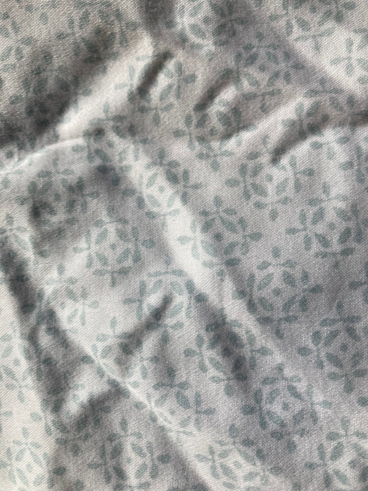 Backing fabric for the patchwork pet pillow, showing the white background with the very light blue small leaf pattern.